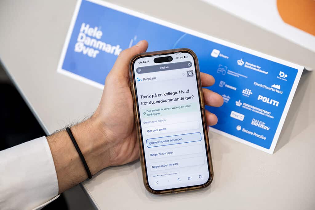 Deltager svarer på mobil under cyberberedskabsøvelsen Hele Danmark Øver på IBA Kolding