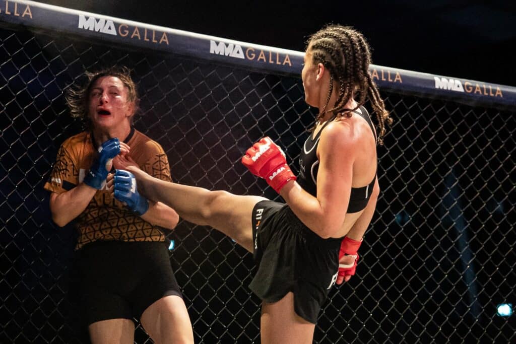 Kvindelig MMA-fighter sparker modstander i MMA Galla buret